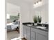 Bathroom boasts gray cabinets, double sinks, a large mirror, and decor, connecting to a bedroom with a king bed at 4159 Persian St, Greenwood, IN 46143