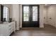 Grand foyer with dark double doors, wood flooring, and a stylish dresser with a mirror, creating an inviting entrance at 4190 Hartswick Ct, Zionsville, IN 46077