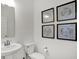 A white powder room with a pedestal sink, toilet, a large mirror, and framed artwork at 4400 Persian St, Greenwood, IN 46143
