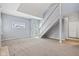 Spacious living room with neutral carpet, stairs, and natural light from a window and door at 455 S Pine St # 4, Indianapolis, IN 46203