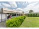 Carport view with a car parked underneath, adjacent to a wooden shed and surrounded by a neatly trimmed hedge and green grass at 4641 Autumn Ridge Dr, Columbus, IN 47203