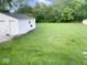 Backyard view featuring a detached white garage with a large yard and green grass at 4943 S State Ave, Indianapolis, IN 46227