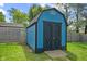 A well-kept blue storage shed boasts black trim and a durable roof, adding practicality and charm at 5115 Bertha St, Indianapolis, IN 46241