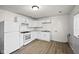 Bright kitchen features white cabinets, appliances, and wood-look flooring, creating a clean and modern space at 611 Hampton Ln, Anderson, IN 46017