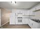 Bright kitchen features white cabinets, appliances, and wood-look flooring, creating a clean and modern space at 611 Hampton Ln, Anderson, IN 46017