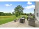 Backyard view featuring a patio with seating, a fire pit, and a well-manicured lawn under a bright, cloudy sky at 7559 Pipestone Dr, Indianapolis, IN 46217