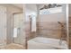 Bright bathroom featuring a shower with glass door, soaking tub with chrome fixtures and decorative tile at 7559 Pipestone Dr, Indianapolis, IN 46217