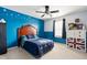 Bright bedroom with blue accent wall, white trim, window, fan, and unique dresser showcasing British flag design at 7559 Pipestone Dr, Indianapolis, IN 46217