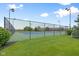 Community tennis court with green and blue surface, surrounded by a black chain-link fence and lush green grass at 7559 Pipestone Dr, Indianapolis, IN 46217