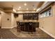 Basement wet bar features a dark wood bar, granite countertops, display shelving, and bar stool seating at 7601 W Stonegate Dr, Zionsville, IN 46077