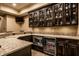 Basement wet bar features a dark wood bar, granite countertops, stainless steel microwave and beverage fridge at 7601 W Stonegate Dr, Zionsville, IN 46077