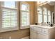 Light-filled bathroom features marble counters, arched windows with white shutters, and vanity storage at 7601 W Stonegate Dr, Zionsville, IN 46077