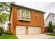 Exterior view of brick home showcasing a three-car garage and mature trees at 7601 W Stonegate Dr, Zionsville, IN 46077