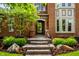 Close-up of the front door entrance featuring stone steps, lush landscaping, and a well-maintained brick facade at 7601 W Stonegate Dr, Zionsville, IN 46077