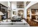 Bright and airy living room showcasing high ceilings, a fireplace, hardwood floors and an open layout to the kitchen at 7601 W Stonegate Dr, Zionsville, IN 46077