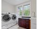 Functional laundry room with modern washer and dryer, storage cabinets, and a bright window at 8100 N Meridian St, Indianapolis, IN 46260