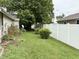 A lush backyard featuring a white fence, green grass, and a mature shade tree, offering privacy and natural beauty at 909 Sullivan St, Alexandria, IN 46001