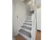 Elegant staircase featuring gray patterned steps, white wood railing, and natural light coming in at 10172 Watkins Ct, Indianapolis, IN 46234