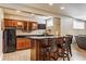 Interior view of a wet bar with wood cabinets, granite counters, wine rack, mini fridge, and bar stool seating at 10784 Giselle Way, Fishers, IN 46040