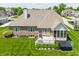 An aerial view shows a brick house with a well-kept lawn, mature trees, and a backyard deck with a hot tub at 10784 Giselle Way, Fishers, IN 46040