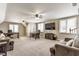 Large, carpeted living room featuring two ceiling fans, a wall-mounted tv and a comfortable seating area with couches and desks at 10784 Giselle Way, Fishers, IN 46040