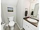 Powder room with stylish grey flooring, framed art, and vanity with white basin sink and wood countertop at 10876 Trailwood Dr, Fishers, IN 46038