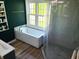 Stylish bathroom showcasing a large white bathtub under a window, complemented by green walls and dark vanity at 13497 Dunes Dr, Carmel, IN 46032
