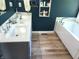 Bathroom featuring a dual sink vanity with modern fixtures and an adjacent bathtub with bright natural light from the window at 13497 Dunes Dr, Carmel, IN 46032