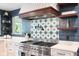 Kitchen stove with custom hood and decorative tile backsplash, with open shelving at 140 Meridian Hills Blvd, Indianapolis, IN 46260