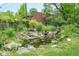 Backyard pond with natural stone and water feature surrounded by lush foliage at 140 Meridian Hills Blvd, Indianapolis, IN 46260