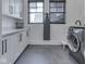 Bright laundry room with cabinetry, dark window frames, and tile flooring at 14464 Gainesway Cir, Fishers, IN 46040