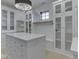 Spacious walk-in closet with custom shelving, storage island, drawers, glass door cabinets and crystal chandelier at 14464 Gainesway Cir, Fishers, IN 46040