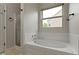 Bright bathroom with a large soaking tub, tile surround, and a window providing natural light at 14542 Baldwin Ln, Carmel, IN 46032