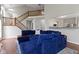 Open-concept living room featuring wood floors, a blue sectional sofa, and staircase view at 14542 Baldwin Ln, Carmel, IN 46032
