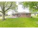 Beautiful backyard featuring a brick home with a wooden deck and vibrant green lawn at 156 N Eastern Village Dr, Greenfield, IN 46140