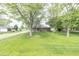 Expansive backyard view of a brick home with mature trees and a well-manicured lawn at 156 N Eastern Village Dr, Greenfield, IN 46140