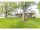 Lush backyard featuring a brick home with a deck and mature trees at 156 N Eastern Village Dr, Greenfield, IN 46140