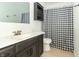 Modern bathroom with a dark vanity, mirror, and a shower featuring a black and white checkered curtain at 156 N Eastern Village Dr, Greenfield, IN 46140
