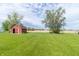 Rustic red shed surrounded by a lush green lawn and mature trees, creating a serene country setting at 156 N Eastern Village Dr, Greenfield, IN 46140