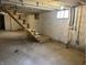 Unfinished basement with concrete flooring, exposed ceiling, and wood staircase at 1718 Thaddeus St, Indianapolis, IN 46203