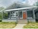 Charming home featuring a covered front porch, gray siding, an orange front door, and manicured lawn at 1718 Thaddeus St, Indianapolis, IN 46203