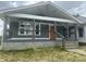 Charming home featuring a covered front porch, gray siding, an orange front door, and manicured lawn at 1718 Thaddeus St, Indianapolis, IN 46203