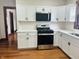 The kitchen features updated stainless steel appliances, with white cabinets and white countertops with new flooring at 1718 Thaddeus St, Indianapolis, IN 46203
