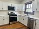 This kitchen features updated appliances, white cabinets, and granite countertops with natural light filling the space at 1718 Thaddeus St, Indianapolis, IN 46203