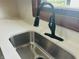 A modern faucet is paired with a stainless steel sink and quartz countertop for an updated kitchen design at 1718 Thaddeus St, Indianapolis, IN 46203