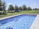 Sparkling blue swimming pool surrounded by a concrete deck and lush greenery at 1751 S Centennial Ave, New Palestine, IN 46163