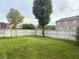 Large, green backyard enclosed by a white fence, surrounded by mature trees, with other homes in the background at 1774 Blue Grass Pkwy, Greenwood, IN 46143