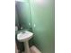 Compact powder room with a pedestal sink and a decorative mirror, complemented by fresh green walls at 1774 Blue Grass Pkwy, Greenwood, IN 46143