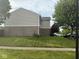Exterior view with lush lawn, mature trees, and a glimpse of parked cars near the home at 1774 Blue Grass Pkwy, Greenwood, IN 46143