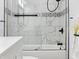 Bathroom bathtub and shower with marble tile and sleek glass doors, paired with black fixtures and accents at 1837 S East St, Indianapolis, IN 46225